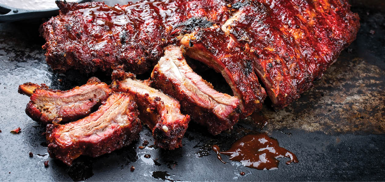Barbecue pork spare loin ribs St Louis cut with hot honey chili marinade burnt as closeup on an old rustic board 