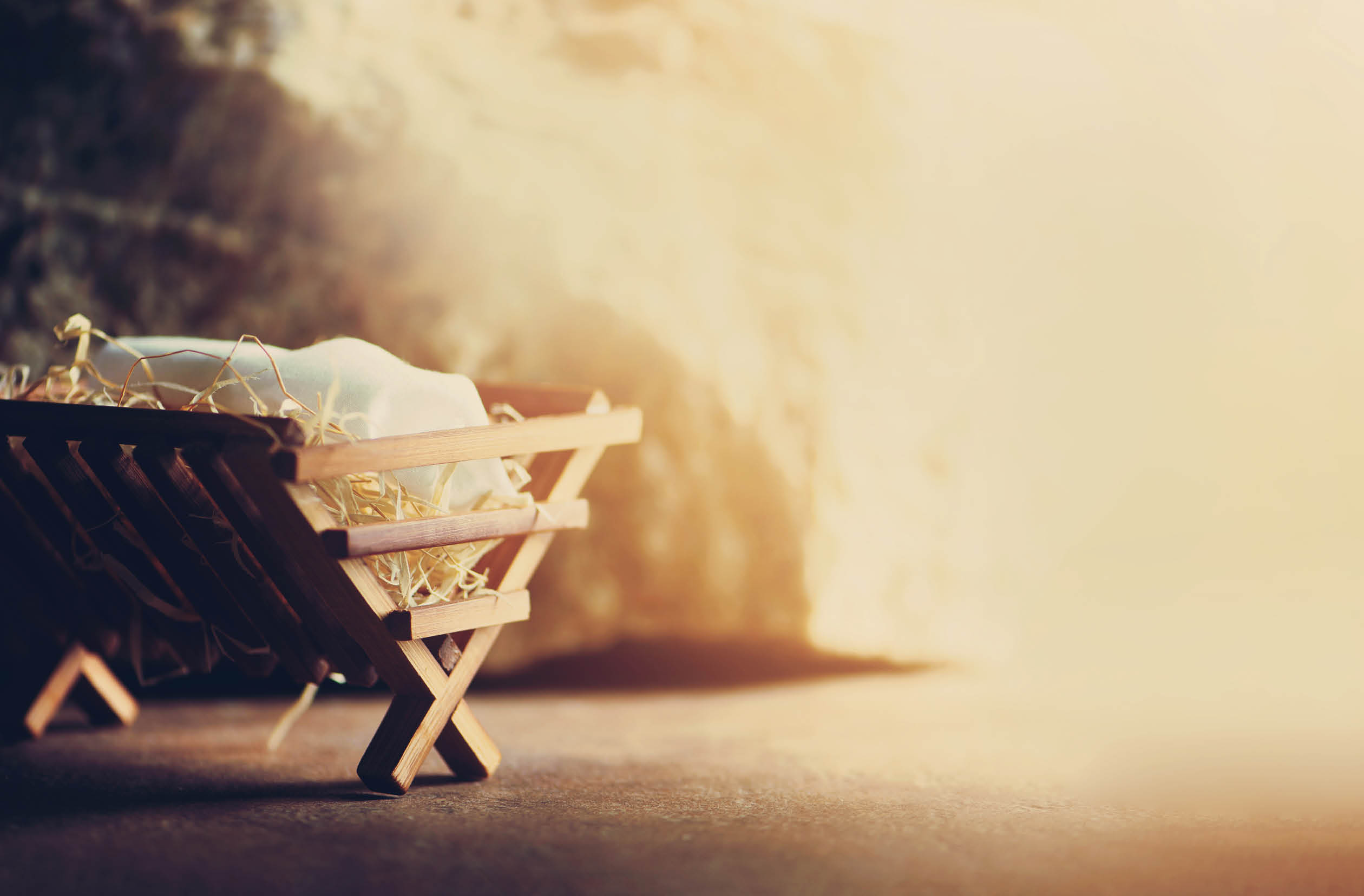 Nativity scene. Christian Christmas concept. Birth of Jesus Christ. Wooden manger in cave background. Banner, copy space. Jesus is reason for season. Salvation, Messiah, Emmanuel, God with us. Gloria.