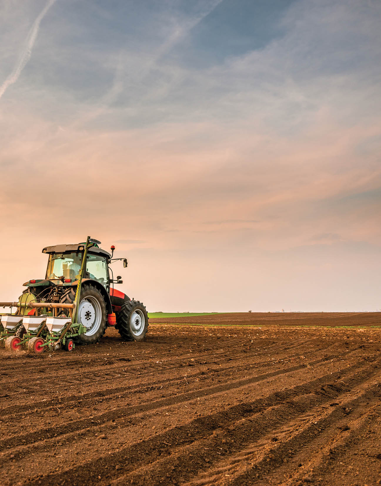 Tractor drilling seeding crops at farm field. Agricultural activity.